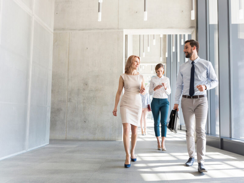 3 people walking down hallway of building