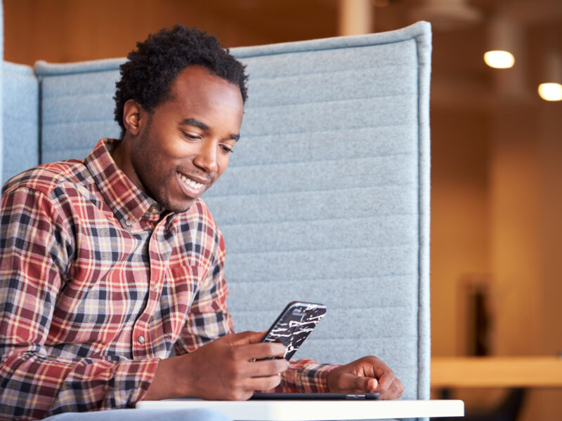 man at desk smiling at phone