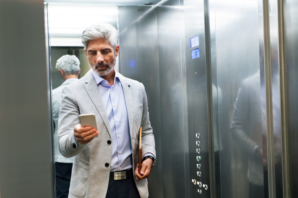 old man in elevator holding phone