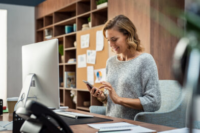 woman at desk holding phone