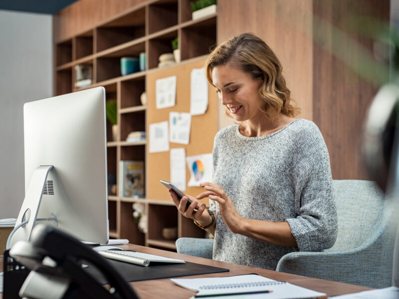 woman at desk holding phone