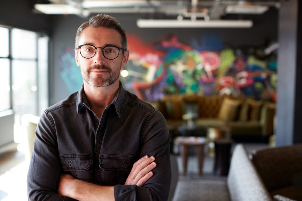 tech guy with arms crossed and office in background