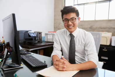 man sitting at desk smiling