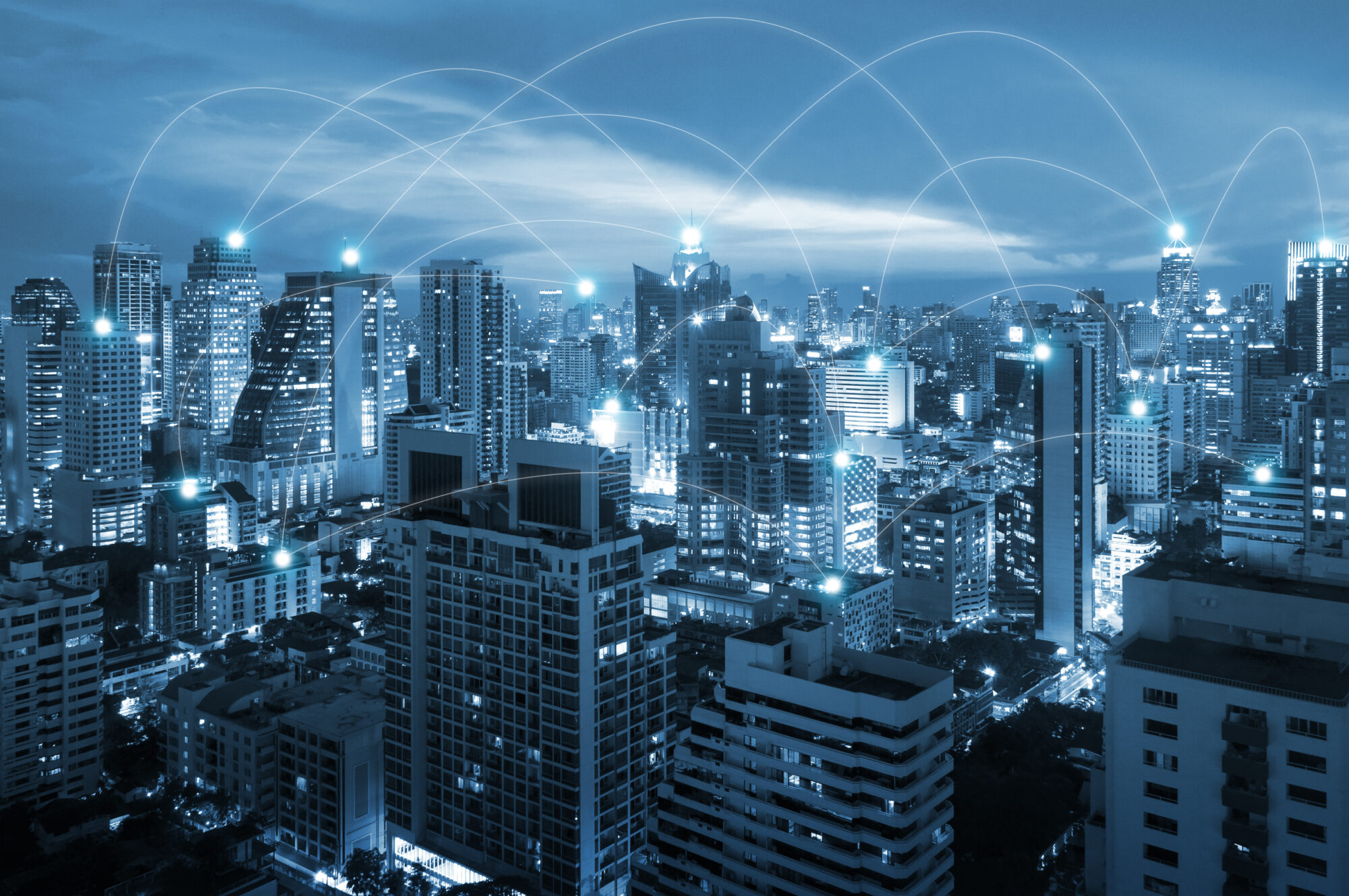 A cityscape at dusk with a digital network overlay sets the scene for a vibrant February. Tall buildings are illuminated, and glowing lines connect various points in the sky, symbolizing connectivity much like insights shared during a shop talk webinar on urban communication.