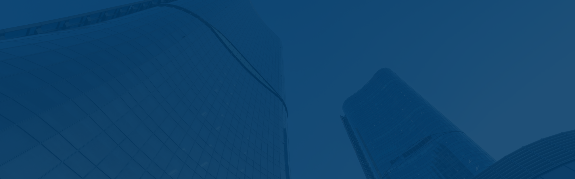 Two modern glass skyscrapers, home to a Top Workplace, soar upward against a blue-tinted sky.